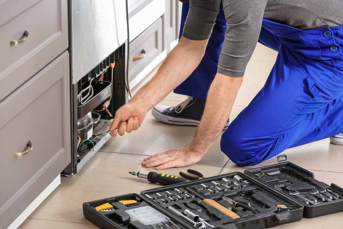 Appliance repair technician working on a fridge